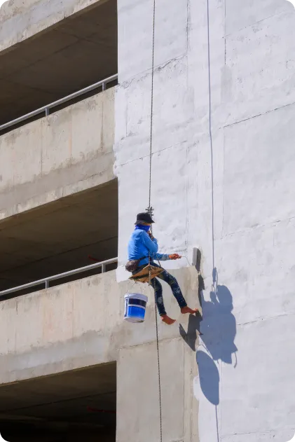 Homem pintando prédio fazendo rapel